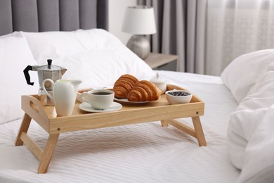 Photo of Wooden tray with tasty breakfast on bed at home