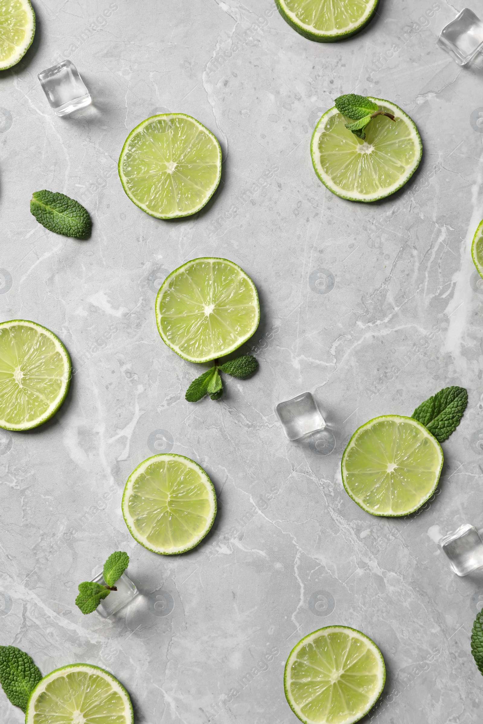 Photo of Flat lay composition with slices of fresh juicy limes on marble table