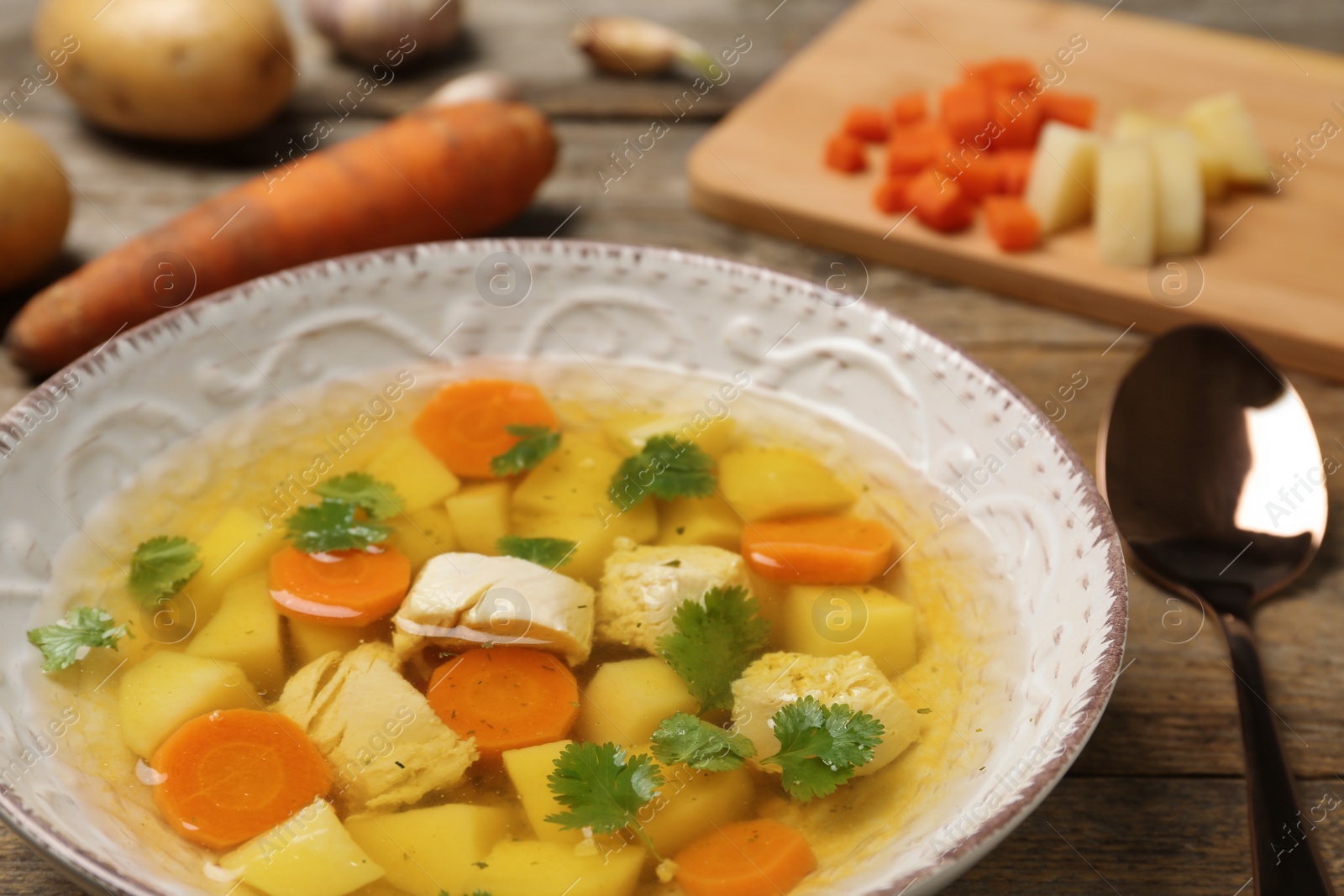 Photo of Dish with fresh homemade chicken soup on wooden table, closeup