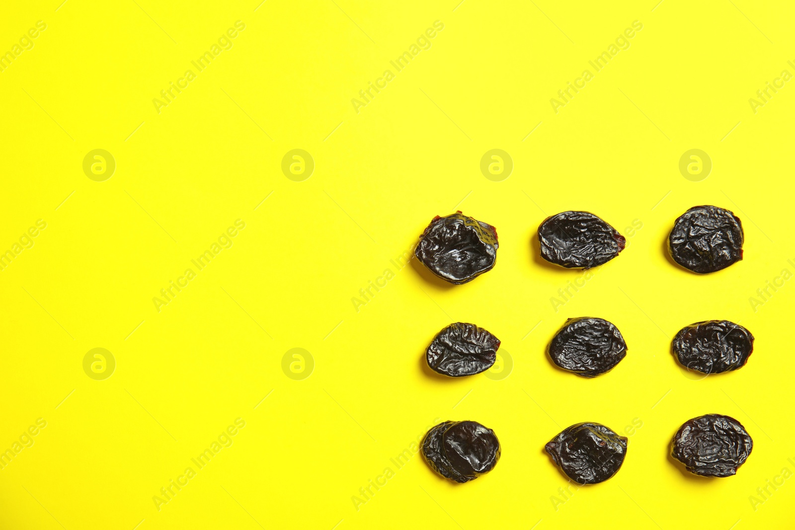 Photo of Flat lay of dried plums on color background, space for text. Healthy fruit