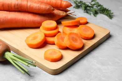 Whole and sliced fresh ripe juicy carrots on light grey marble table, closeup