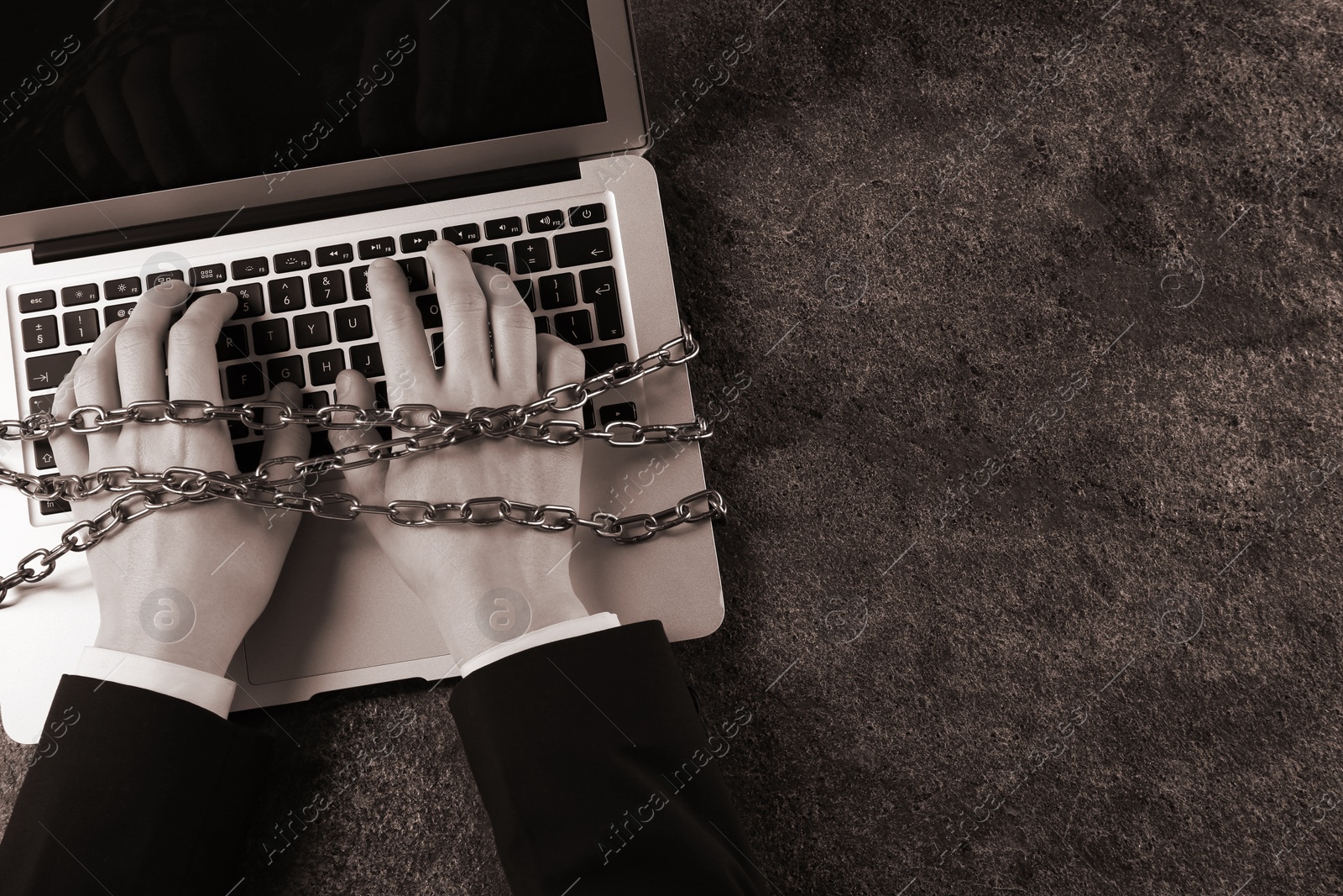 Image of Top view of internet addicted woman with chained hands using laptop at grey table, space for text. Sepia effect