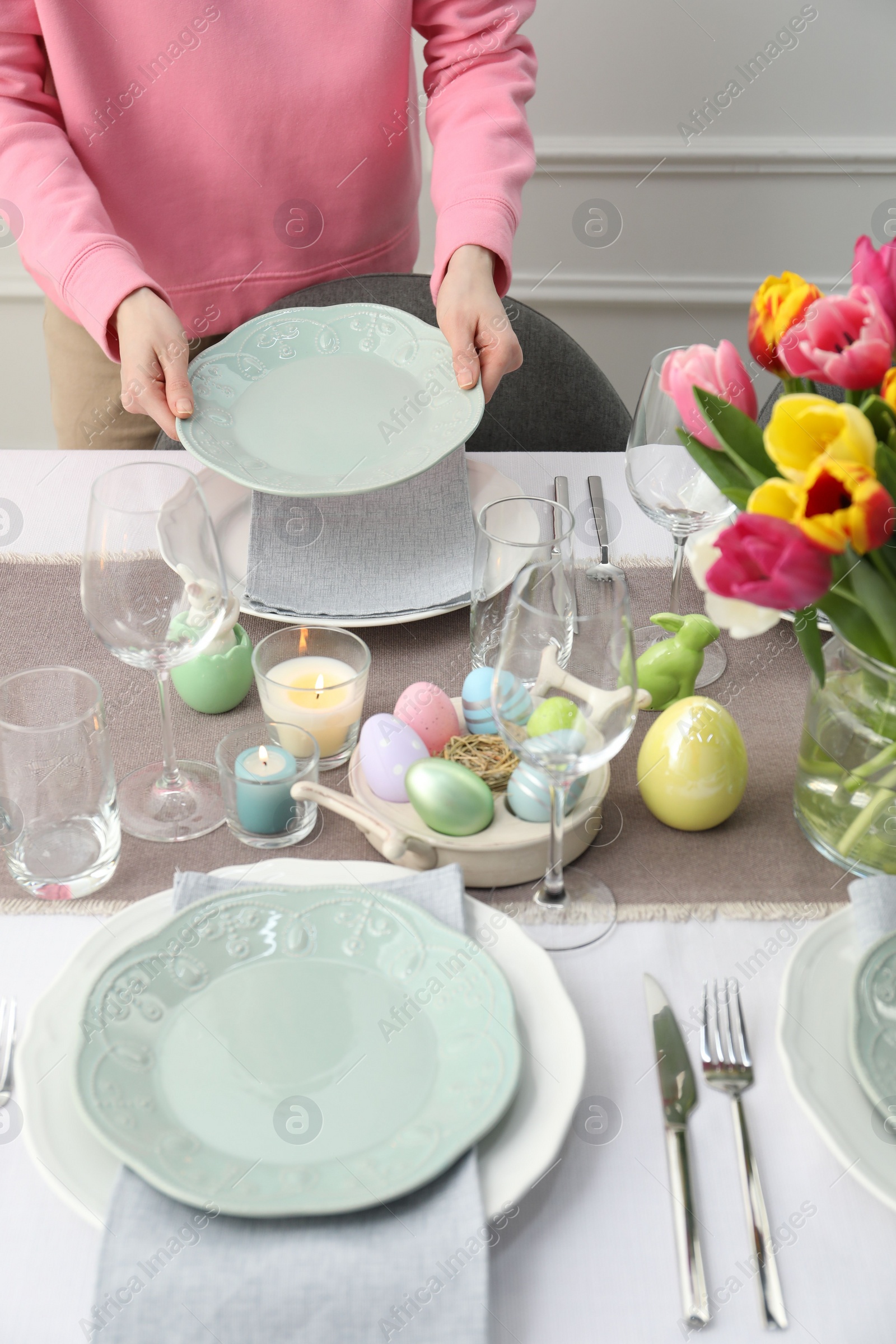 Photo of Woman setting table for festive Easter dinner at home, closeup