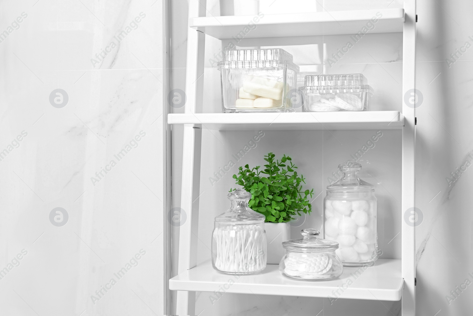Photo of Cotton swabs and other hygiene products on shelving unit in bathroom
