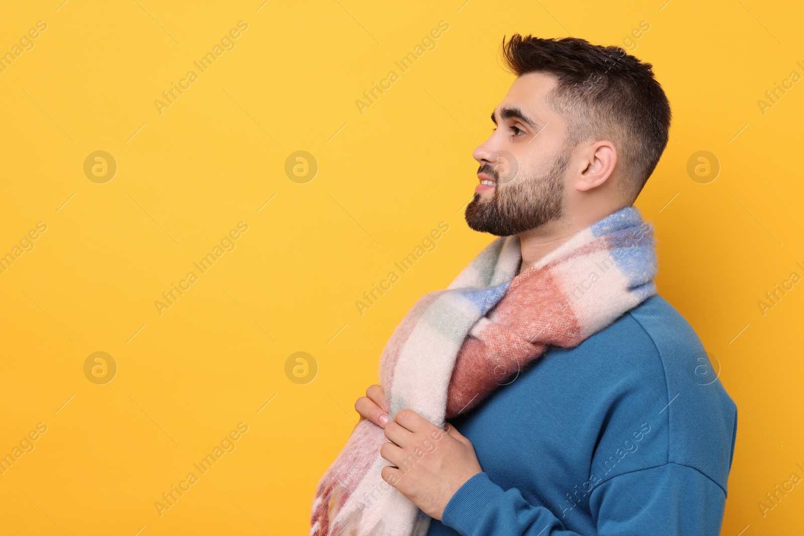 Photo of Handsome man in warm scarf on yellow background. Space for text