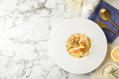 Delicious pasta with shrimps served on white marble table, flat lay. Space for text