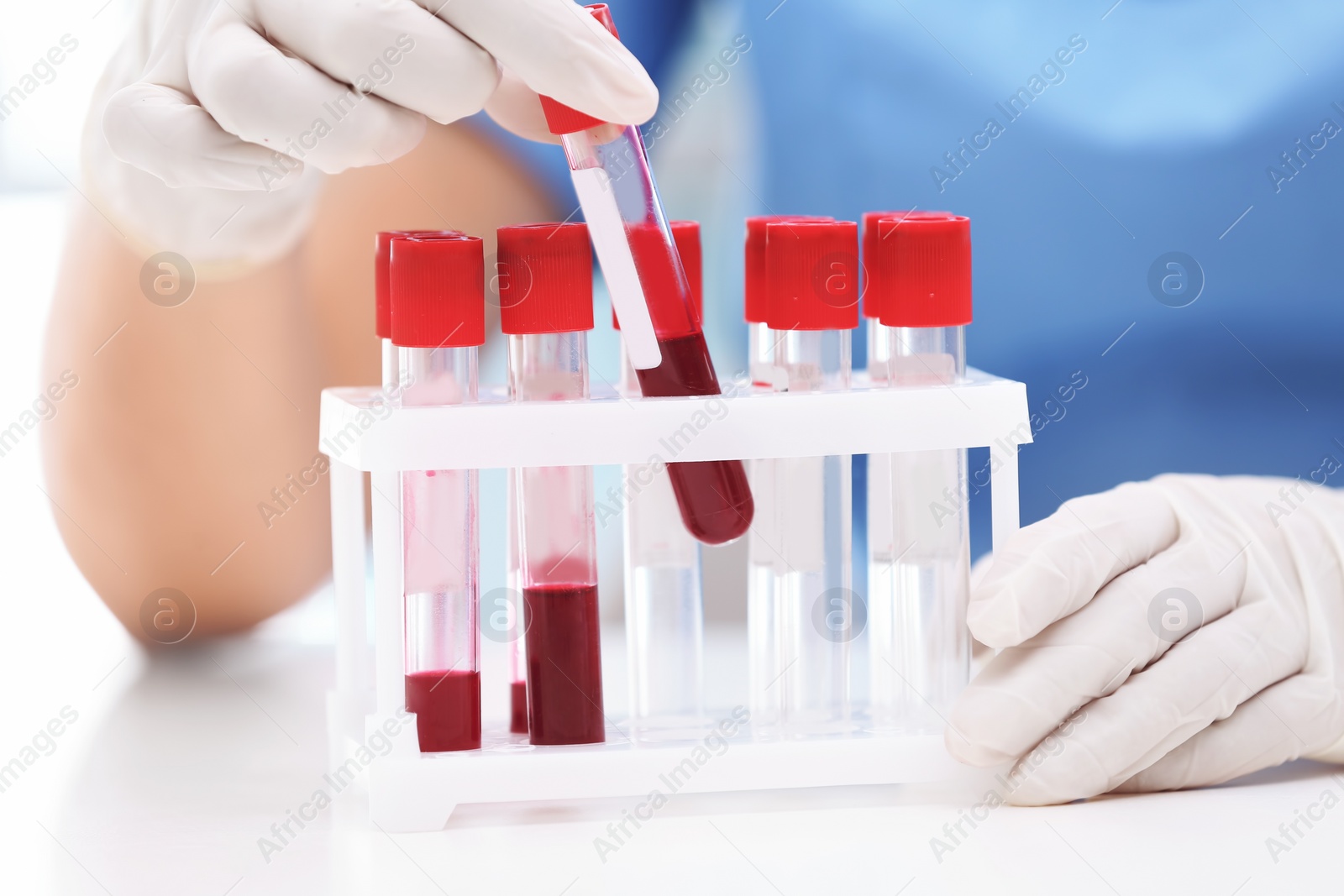 Photo of Scientist holding test tube with blood sample at table in laboratory