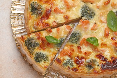 Delicious homemade quiche with salmon and broccoli on beige table, top view