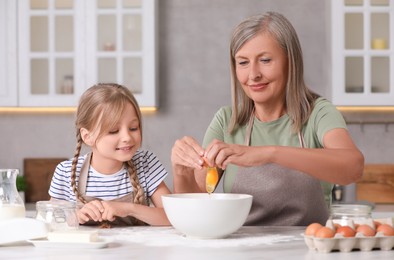 Photo of Happy grandmother with her granddaughter cooking together in kitchen