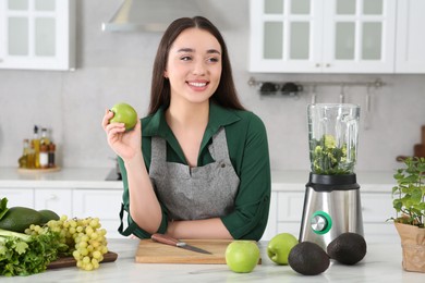 Photo of Beautiful young woman with apples for smoothie at white table in kitchen