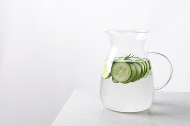 Photo of Jug of fresh cucumber water on table. Space for text