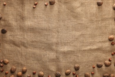 Many walnuts on burlap fabric, top view. Space for text