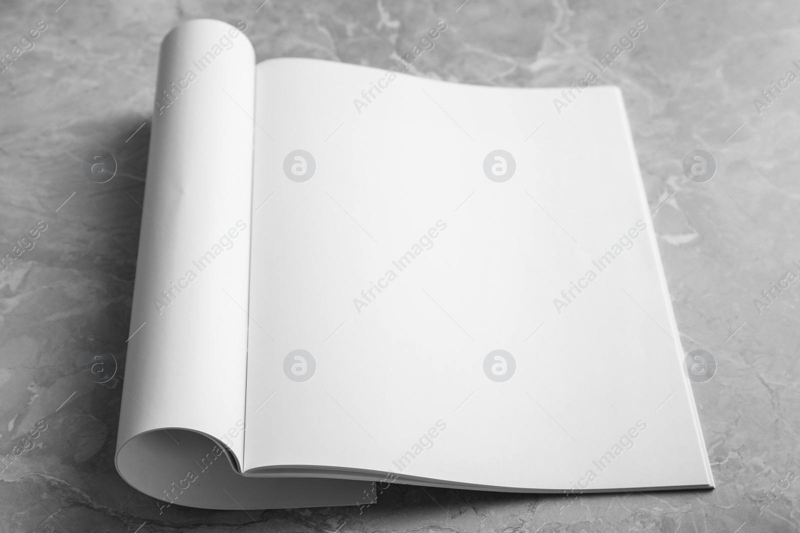 Photo of Blank open book on light grey marble background. Mock up for design