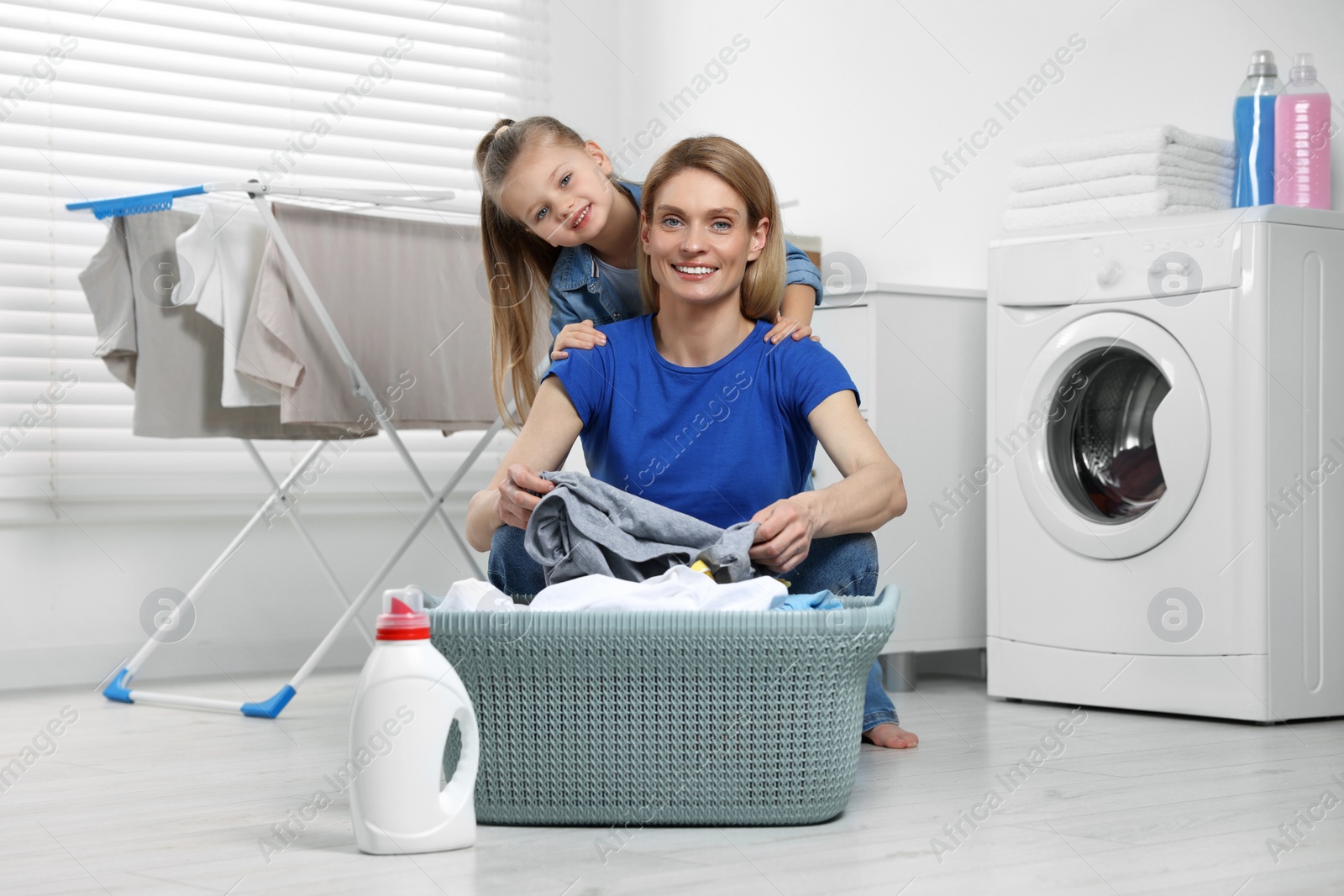 Photo of Mother and daughter taking out dirty clothes from basket in bathroom