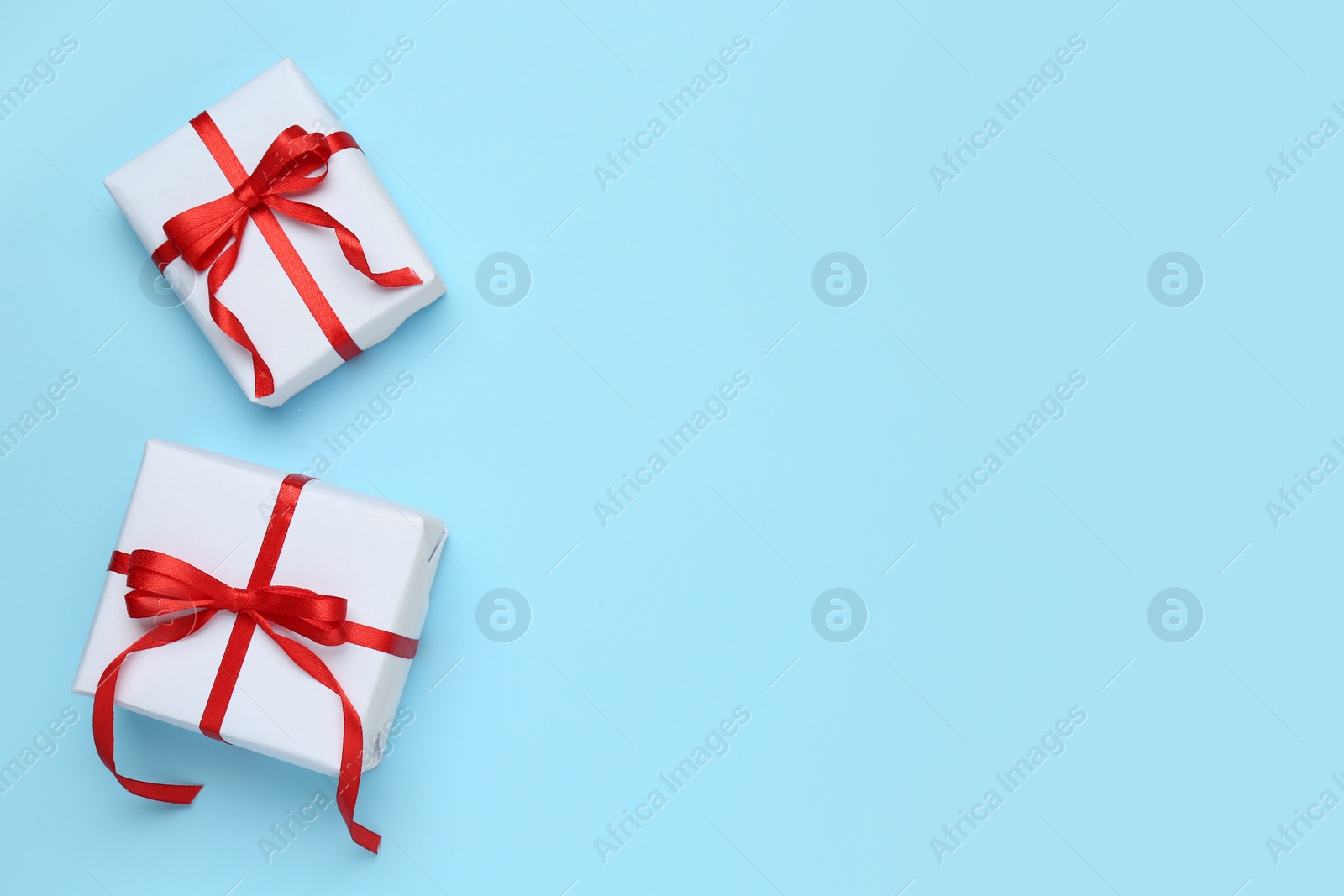 Photo of Beautiful gift boxes on light blue background, flat lay. Space for text