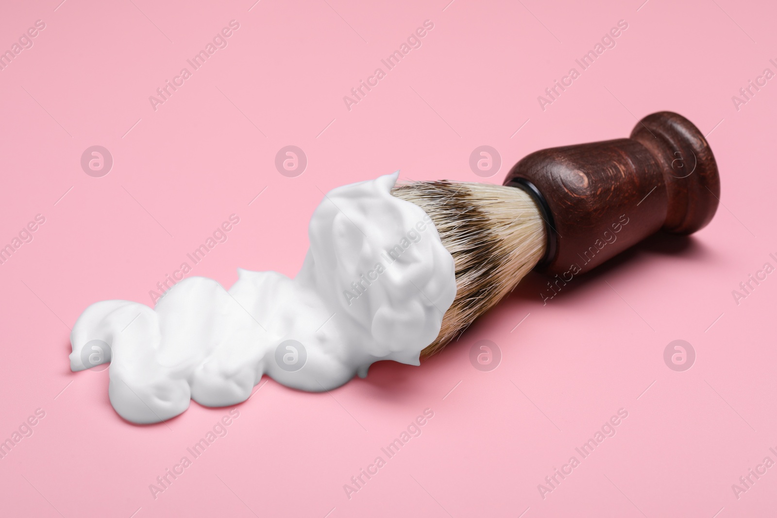 Photo of Brush with shaving foam on pink background, closeup