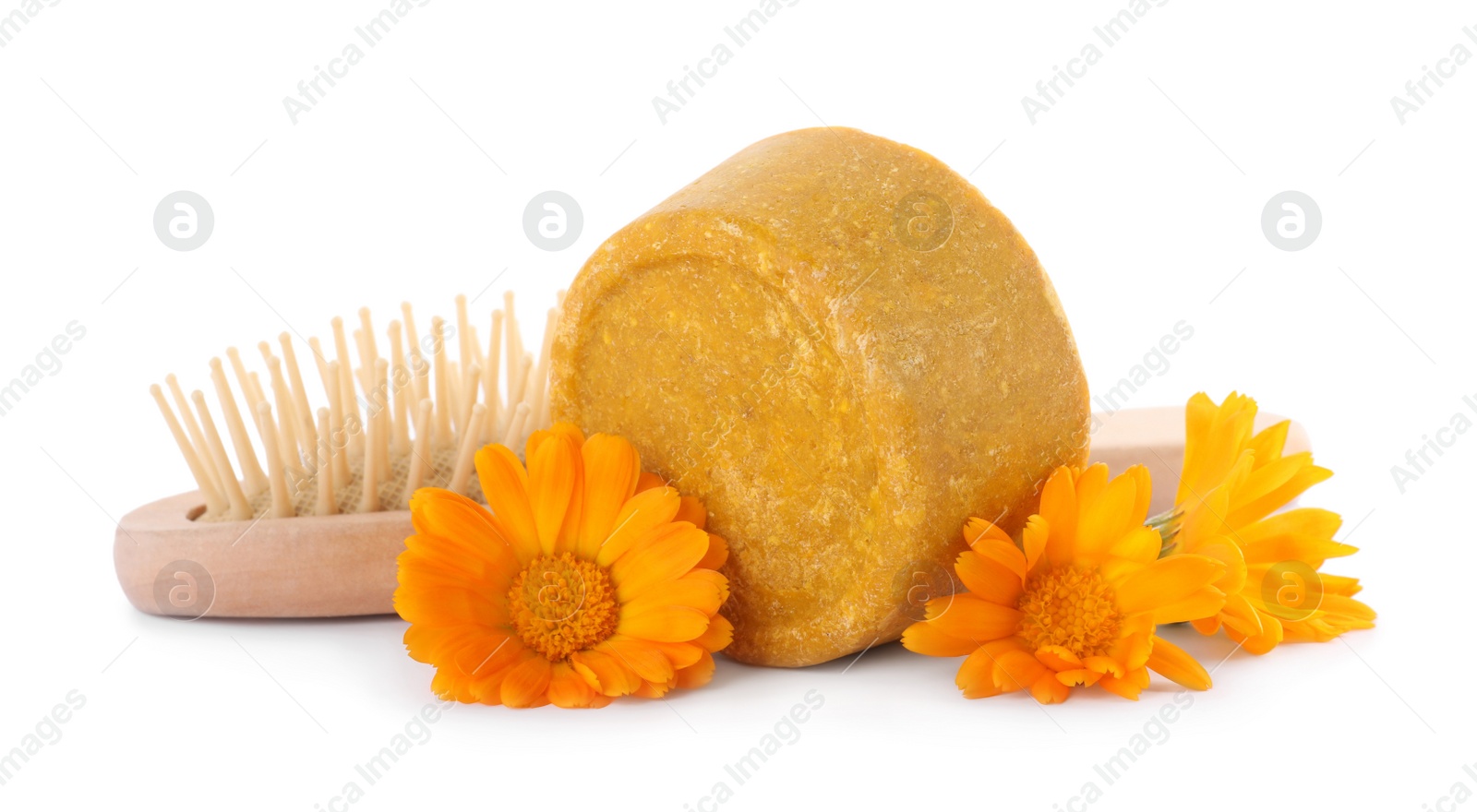 Photo of Yellow solid shampoo bar, hairbrush and flowers on white background. Hair care