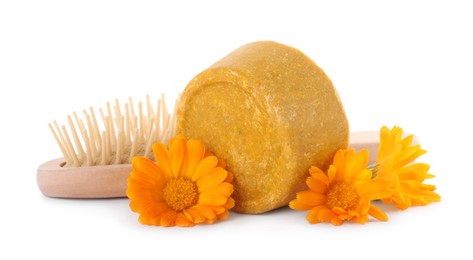 Photo of Yellow solid shampoo bar, hairbrush and flowers on white background. Hair care