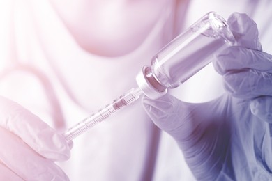 Image of Doctor filling syringe with medication from vial, closeup. Color toned