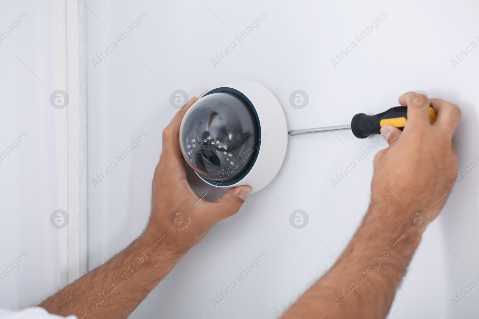 Photo of Technician installing CCTV camera on wall, closeup