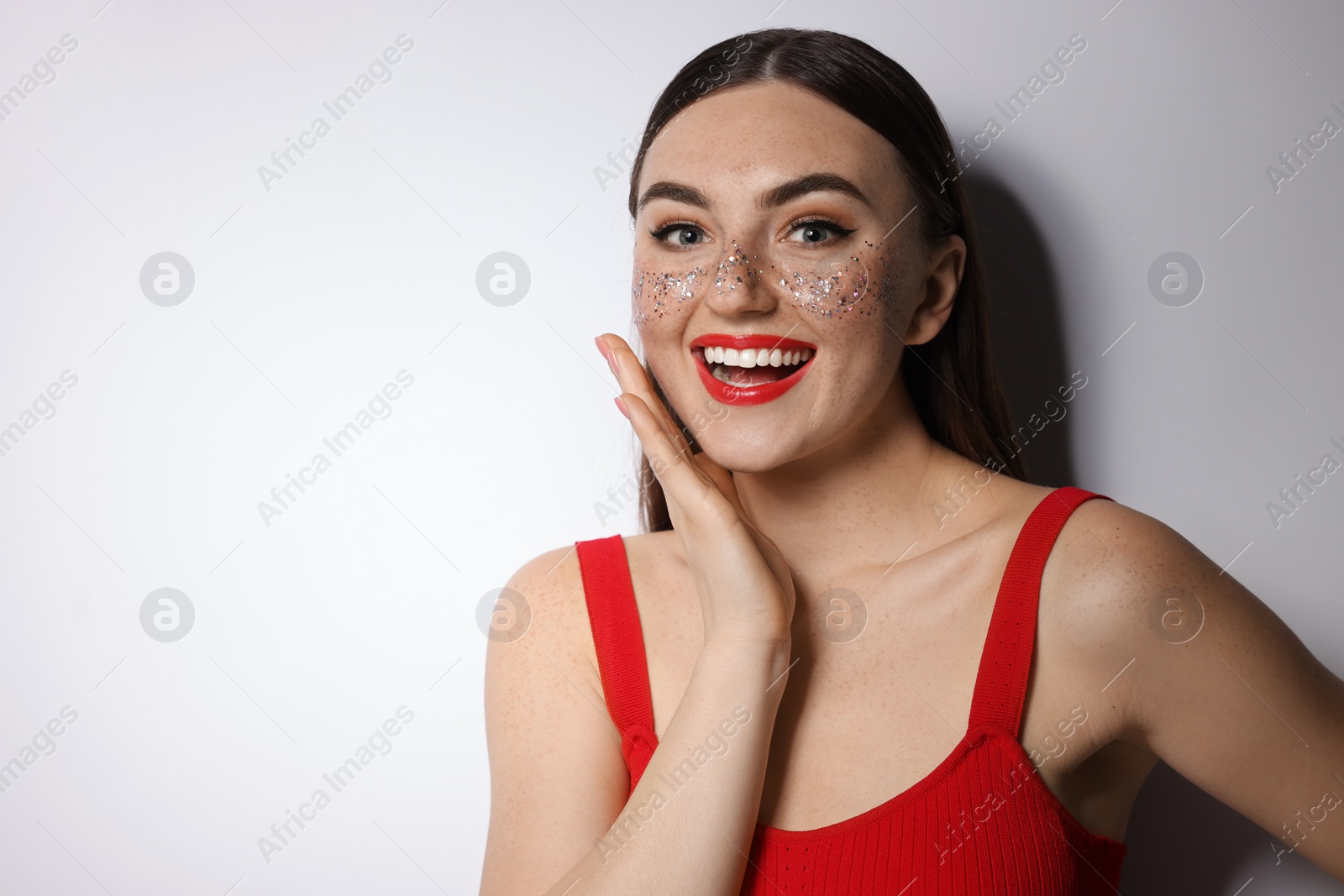 Photo of Happy woman with glitter freckles on light background. Space for text