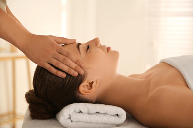 Young woman receiving head massage in spa salon