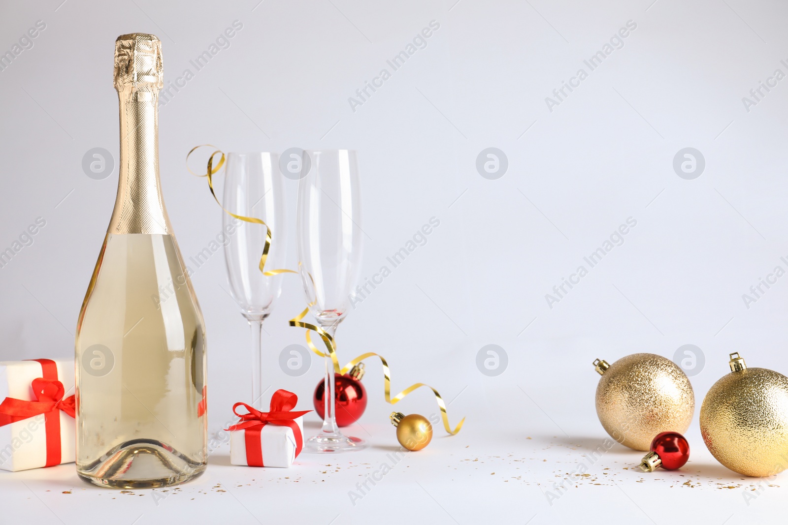 Photo of Happy New Year! Bottle of sparkling wine, glasses and festive decor on white background