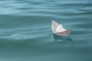 Photo of White paper boat floating on water surface, space for text