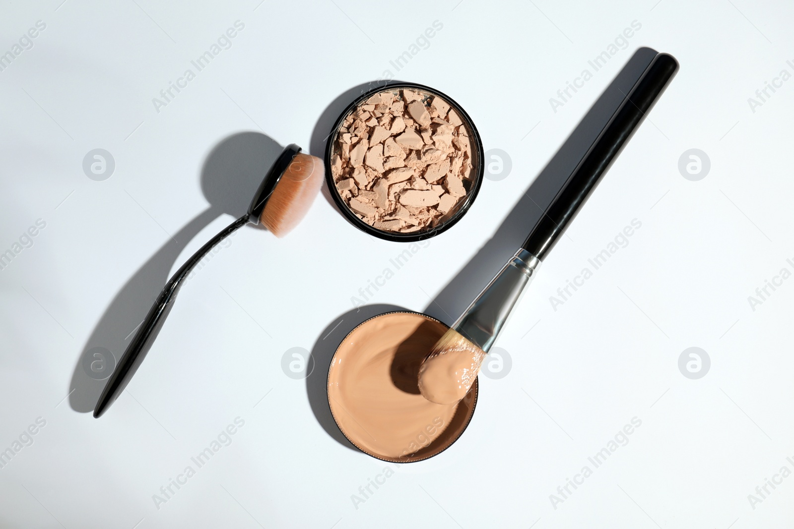 Photo of Skin foundation, powder and brushes on white background, top view