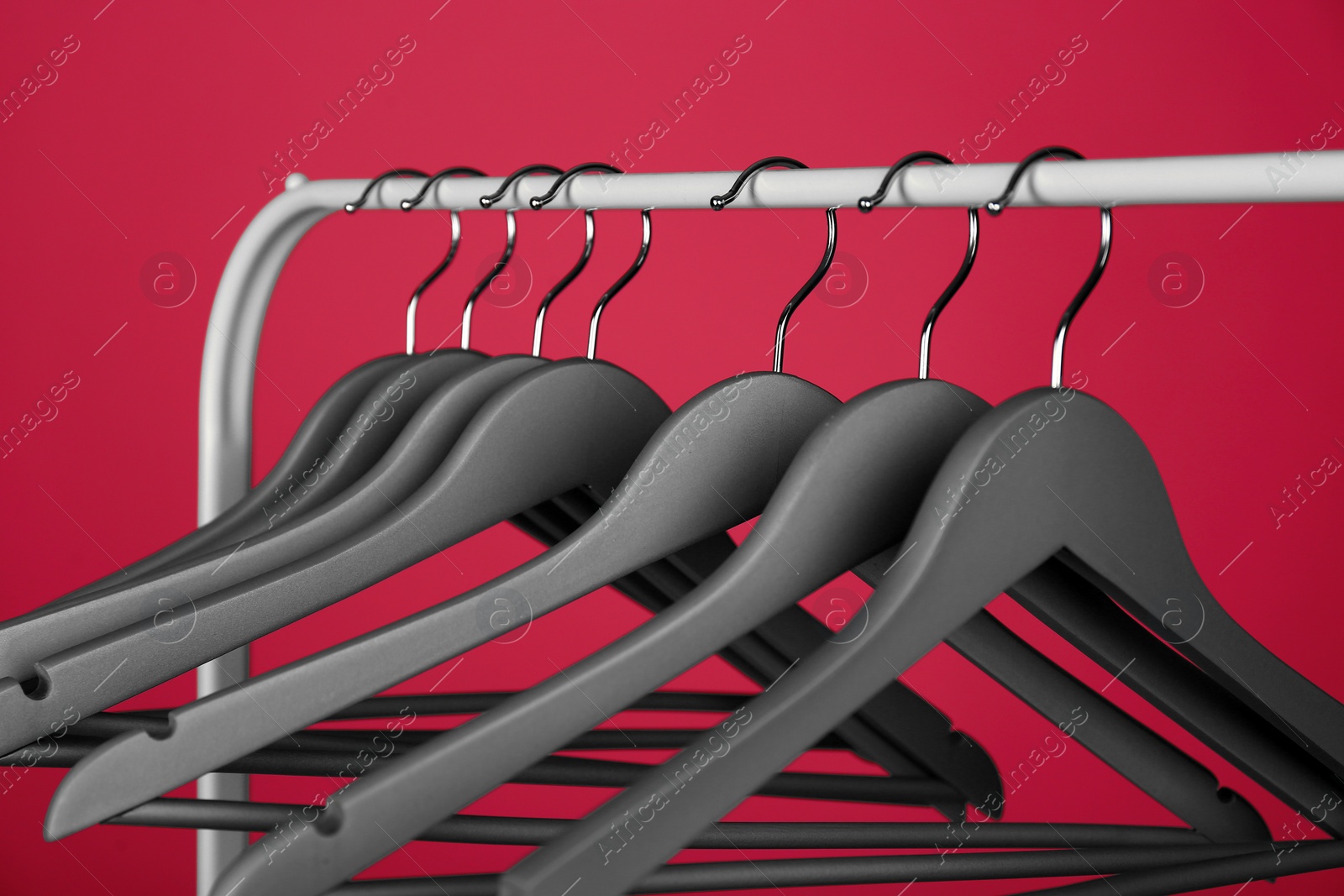 Photo of Empty clothes hangers on metal rack against color background