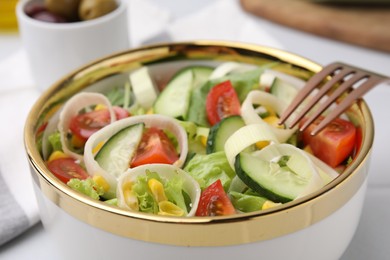 Photo of Bowl of tasty salad with leek, tomatoes and cucumbers on white table, closeup