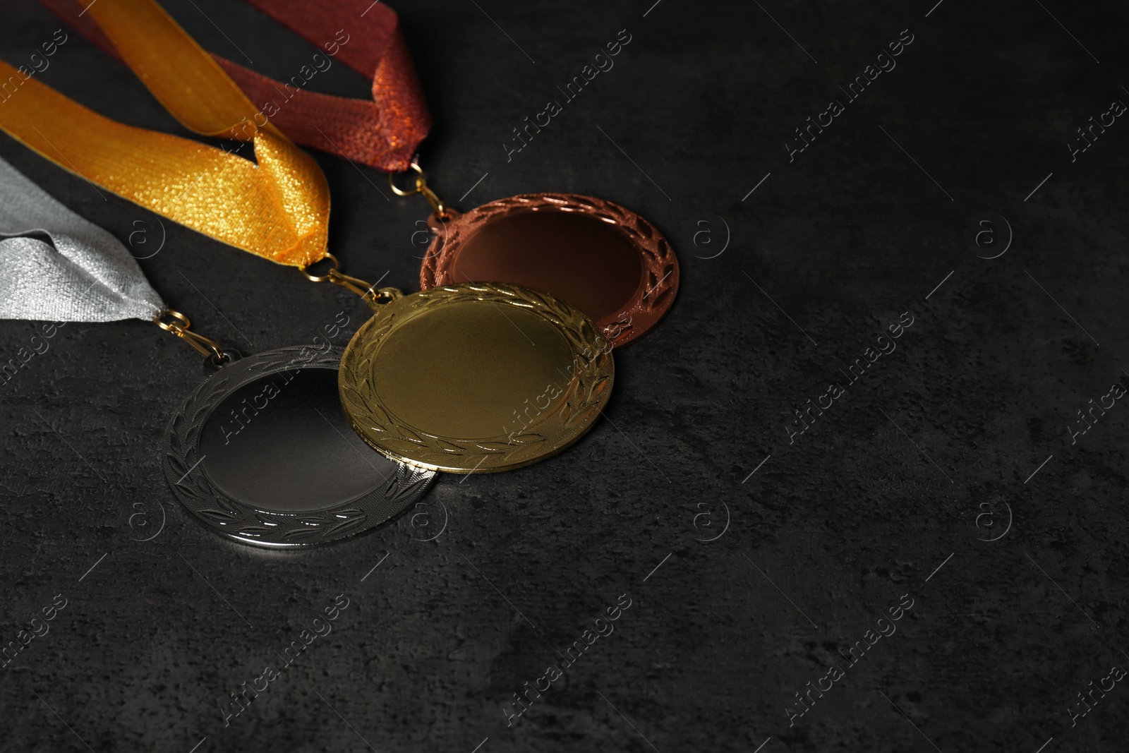 Photo of Gold, silver and bronze medals on grey stone background. Space for design