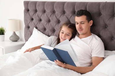 Father reading book with child in bedroom. Happy family