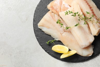 Photo of Pieces of raw cod fish and lemon on light grey table, top view. Space for text