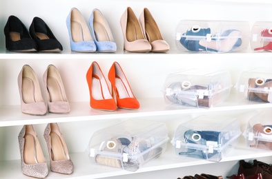 Footwear and plastic boxes on shelves in wardrobe. Shoe storage organization