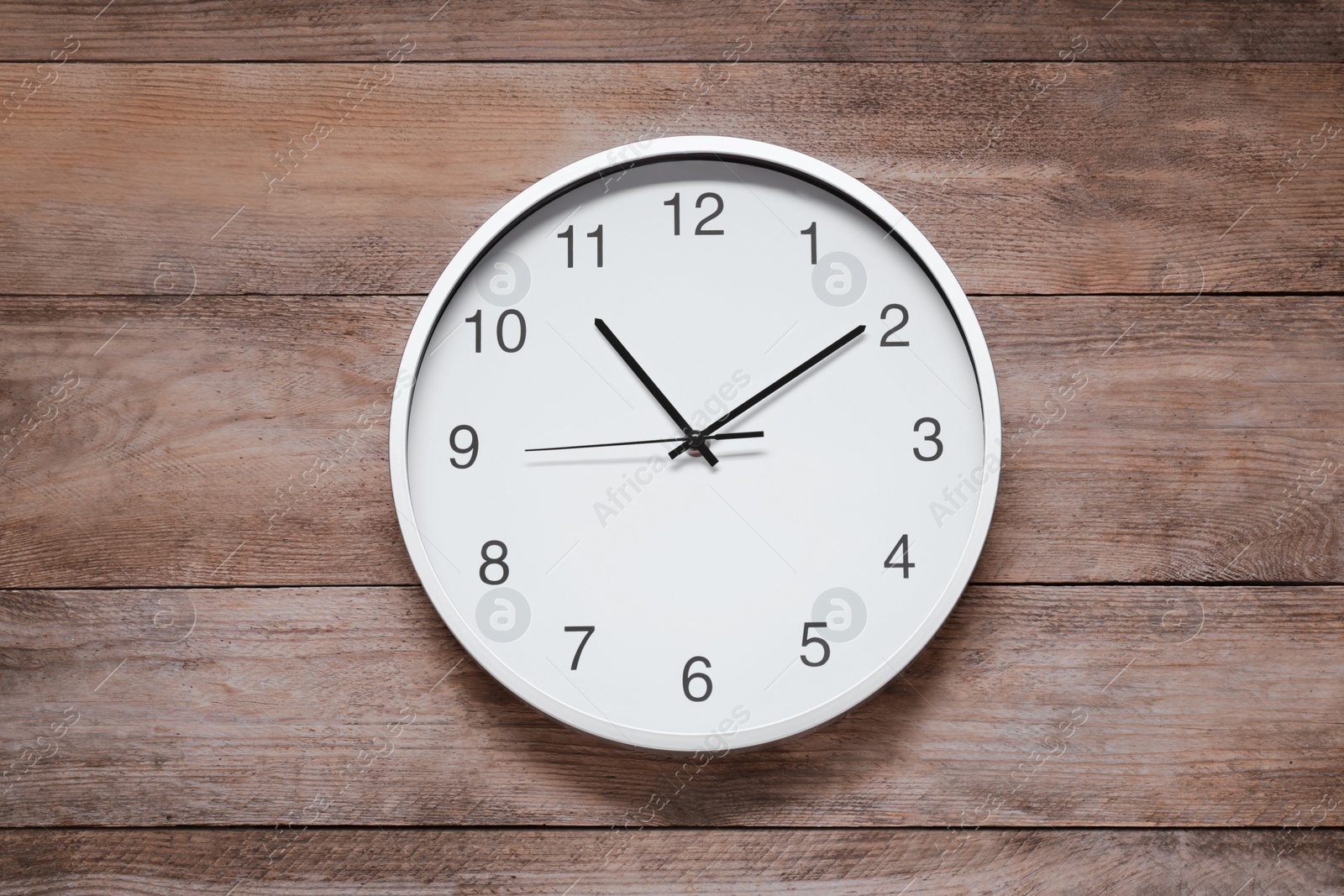 Photo of Stylish round clock on wooden table, top view. Interior element