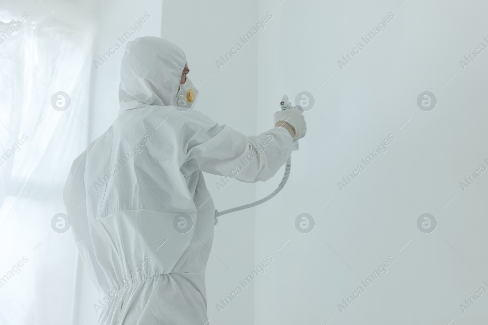 Photo of Decorator painting wall with spray, space for text