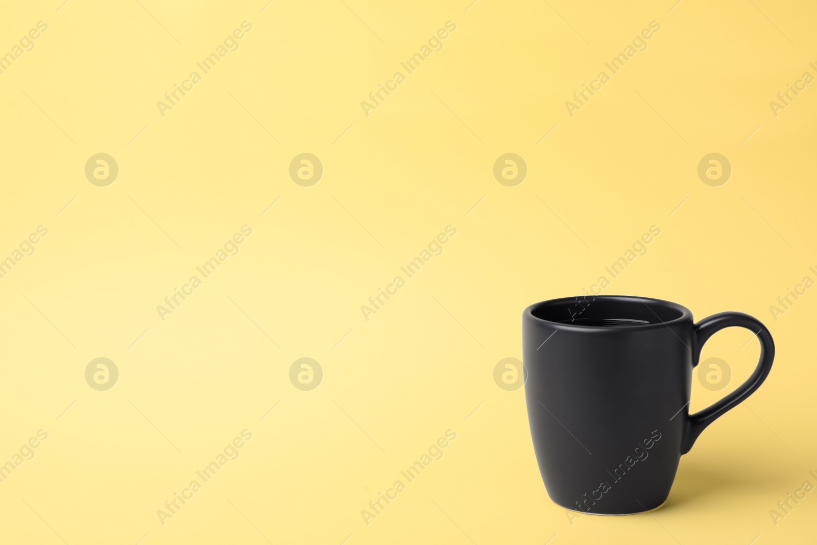 Photo of Black ceramic cup with hot aromatic coffee on color background