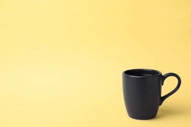 Black ceramic cup with hot aromatic coffee on color background