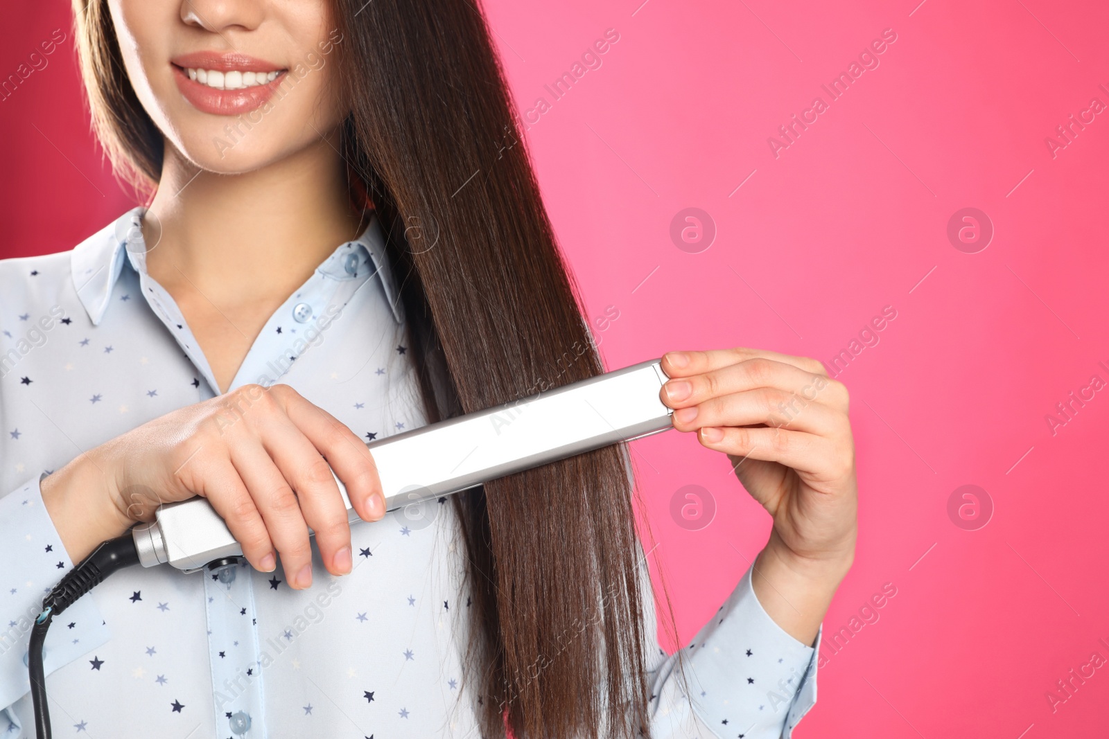 Photo of Happy woman using hair iron on color background, closeup. Space for text