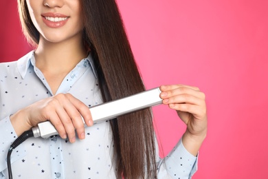 Happy woman using hair iron on color background, closeup. Space for text