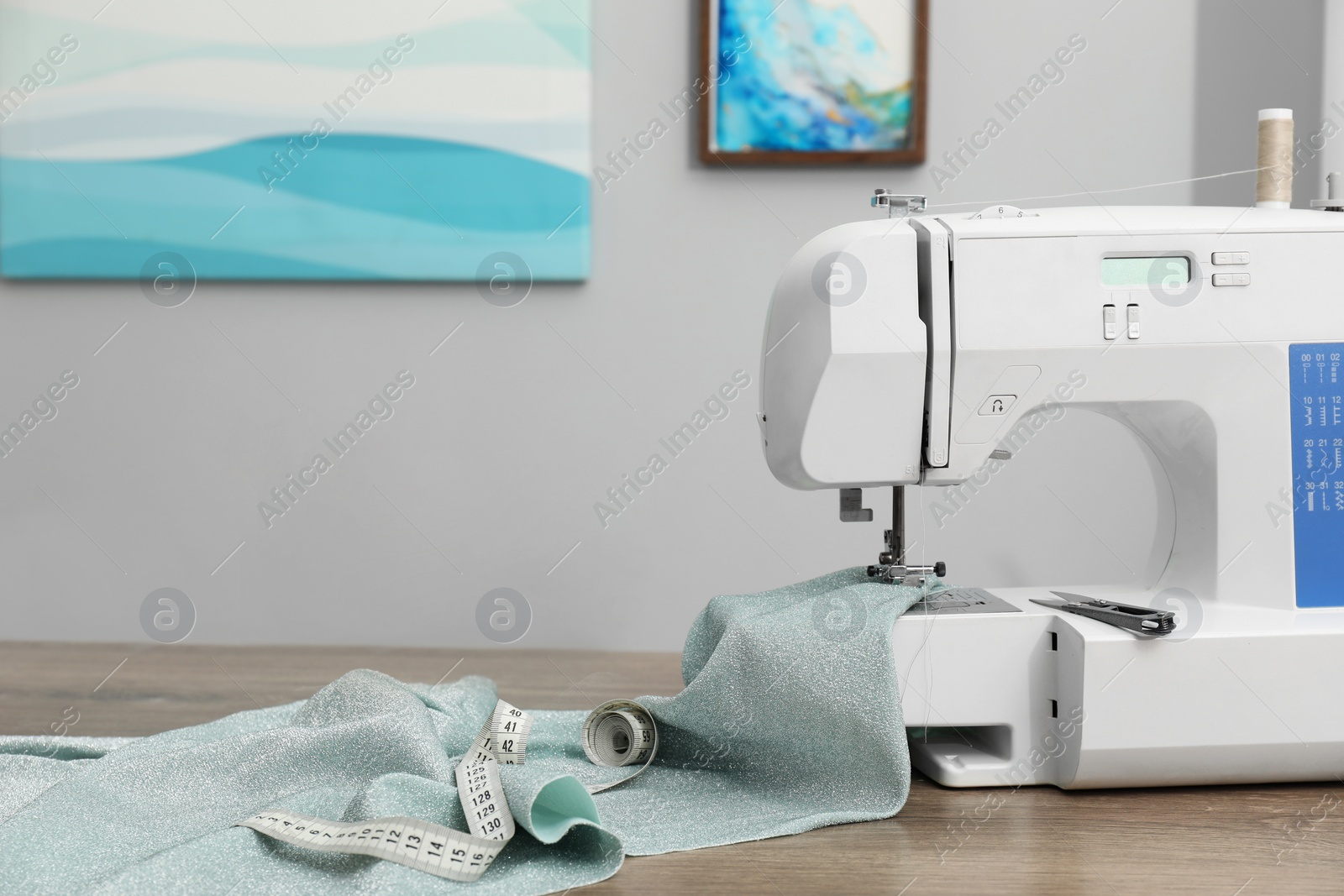 Photo of White sewing machine and cloth on wooden table indoors