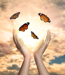 Image of Woman releasing butterflies against beautiful sky outdoors, closeup. Freedom concept