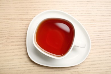 Freshly brewed rooibos tea in ceramic cup on wooden table, top view