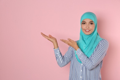 Portrait of young Muslim woman in hijab against color background. Space for text