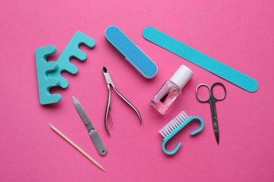 Photo of Set of pedicure tools on pink background, flat lay