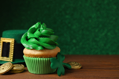 Photo of Composition with delicious decorated cupcake on wooden table. St. Patrick's Day celebration