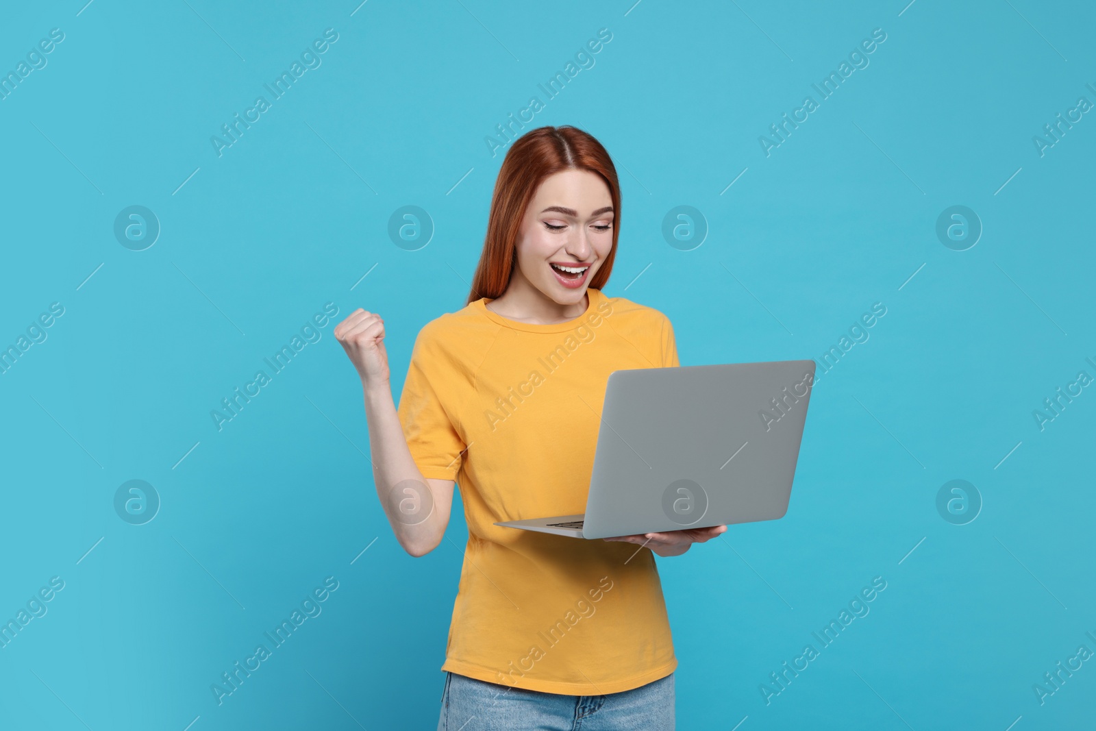 Photo of Happy young woman with laptop on light blue background