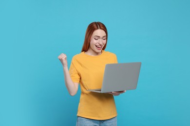 Happy young woman with laptop on light blue background