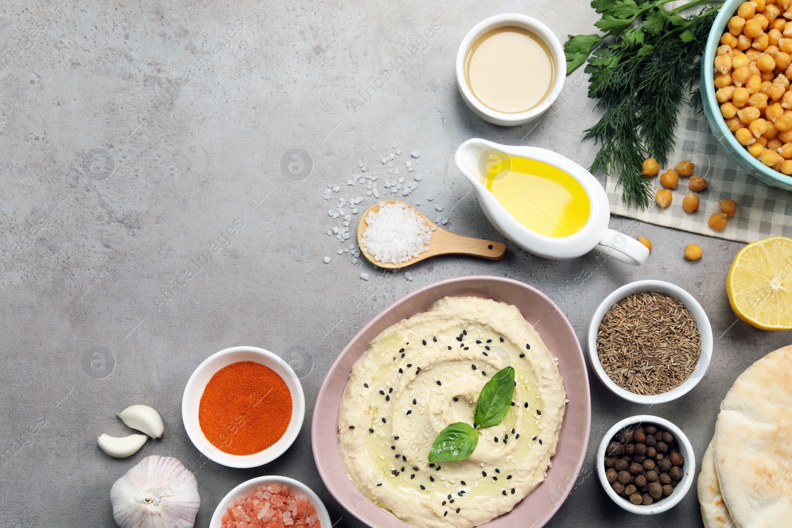 Photo of Delicious creamy hummus with sesame and different ingredients on light grey table, flat lay. Space for text